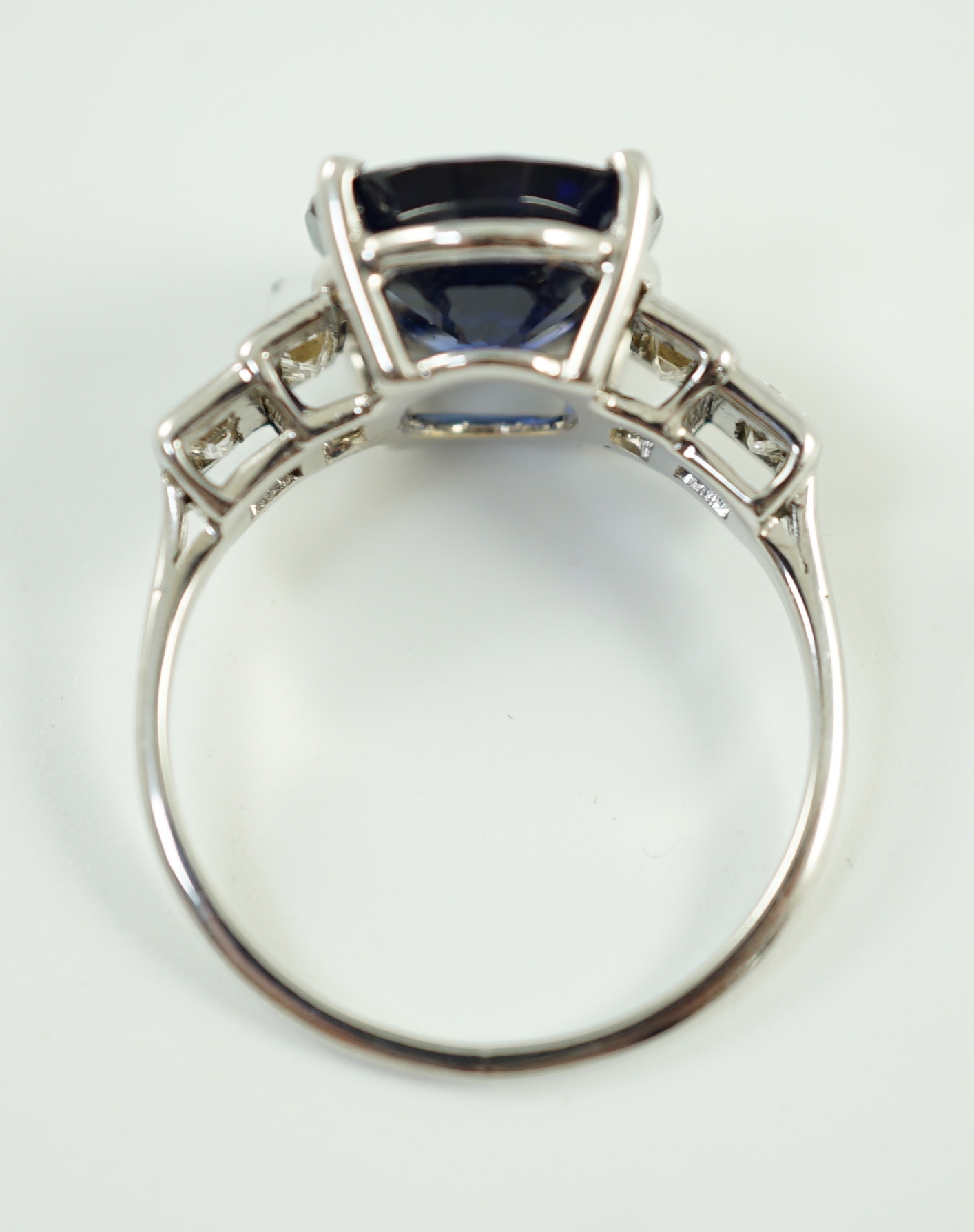 A platinum and single stone oval cut sapphire set cocktail ring, with graduated four stone baguette cut diamond set shoulders